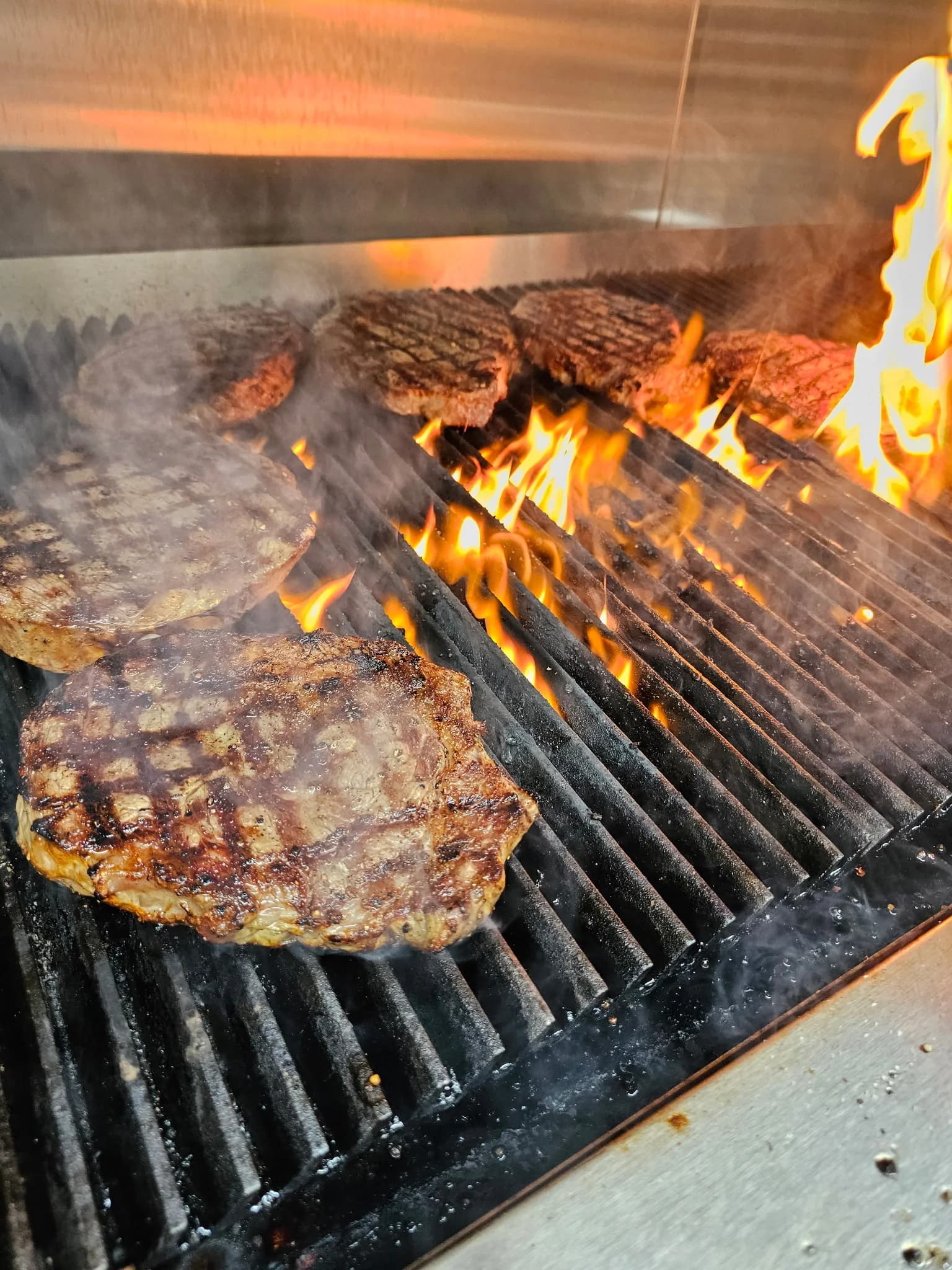 Steaks cooking over the open-flame grill at SPUR Restaurant & Bar